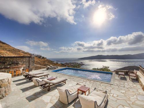 Agios Sostis MykonosにあるGorgeous Villa in Mykonos with Private Poolの水辺の景色を望むスイミングプール(椅子付)