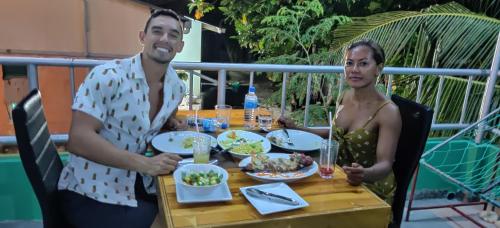 a man and a woman sitting at a table with food at Athens View Hotel in Guraidhoo