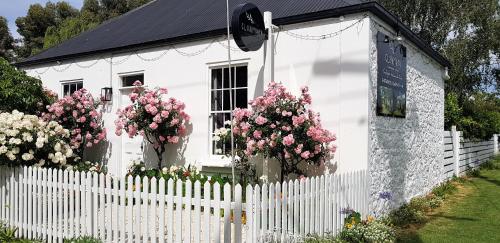 a white house with flowers in front of a fence at Clonmara Country House and Cottages in Port Fairy