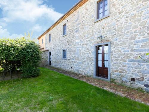 - un bâtiment en pierre avec une cour en gazon devant dans l'établissement Belvilla by OYO Quercia, à Cortone