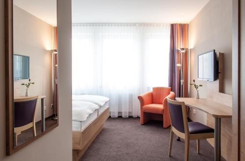 a hotel room with a bed and a desk and a mirror at Gasthaus Alte Münze in Zwickau