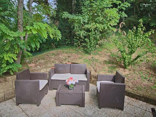 two wicker chairs and a table with flowers on a patio at Flat with swimming pool garden BBQ and parking in Arcevia