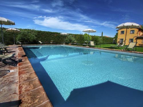 a large swimming pool with chairs and umbrellas at Belvilla by OYO Cipresso in Cortona