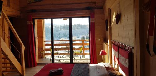 1 Schlafzimmer mit einer Tür, die auf einen Balkon mit einem Tisch führt in der Unterkunft Le Jura en toutes saisons piscine, SPA, climatisation, balades 2cv in Bonlieu