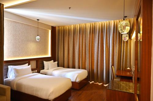 Habitación de hotel con 2 camas y cortinas en Pristine Hotel, Varanasi, en Varanasi