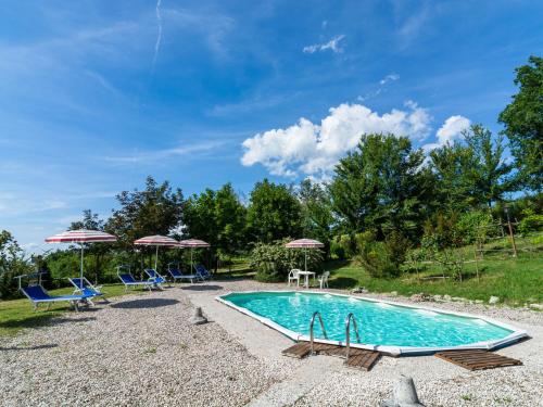 uma piscina com cadeiras azuis e guarda-sóis em Belvilla by OYO La Cinciallegra em Acqualagna