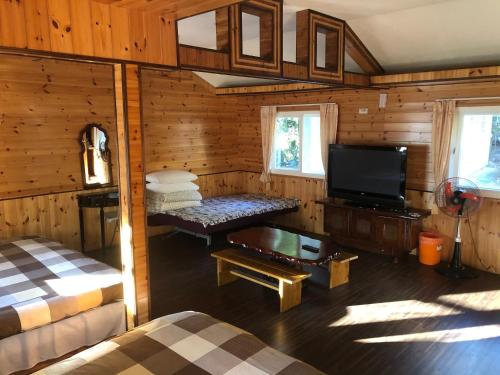 a room with a bed and a tv in a cabin at 溪景生態農莊 桃園市民宿037號 in Hualing