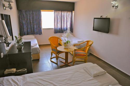 a room with a bed and a table and a tv at Aquamarine Hotel in Eilat