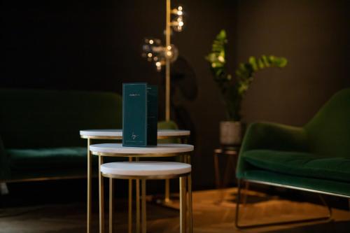 two tables in a room with two green chairs at 133 Boutique Hotel in Karlsruhe