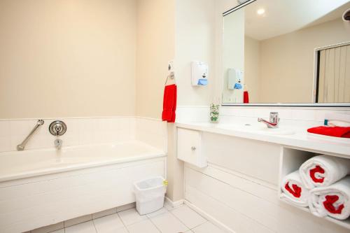 a white bathroom with a tub and a sink at Cascades Lakefront Motel in Taupo
