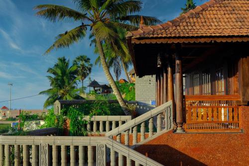 a house with a fence and a palm tree at AyurSoma Ayurveda Royal Retreat in Kovalam