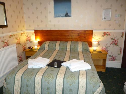 a hotel room with a bed with two towels on it at Weybourne Guest House in Tenby