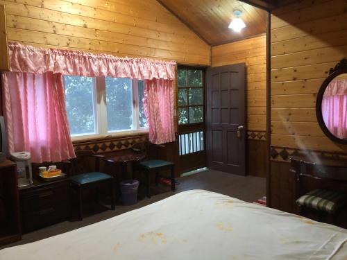 a bedroom with a bed and a desk and windows at 溪景生態農莊 桃園市民宿037號 in Hualing