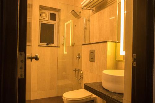 a bathroom with a toilet and a shower and a sink at Encore Suites Goa in Panaji