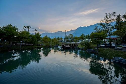 a river with a bridge and mountains in the background at Fanlin House in Jialin