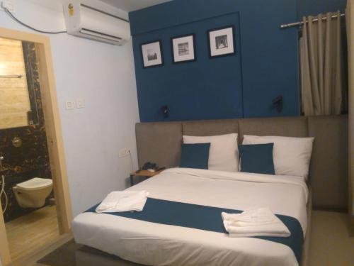 a bedroom with a large bed with blue walls at Hotel Mayfair Tower in Kolkata