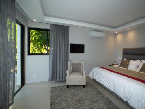 a bedroom with a bed and a chair and a window at Hout Bay View Boutique Hotel in Hout Bay