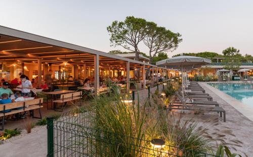 a restaurant with a pool and people sitting at tables at Mediterraneo Camping Village in Cavallino-Treporti