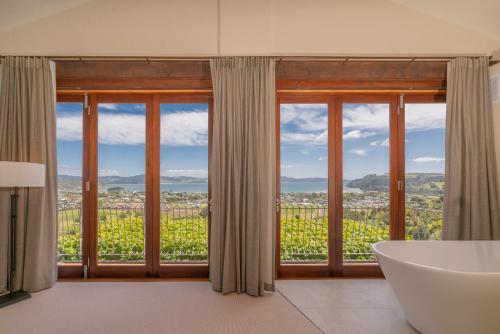 a bathroom with a tub and a large window with a view at Mercury Ridge in Cooks Beach