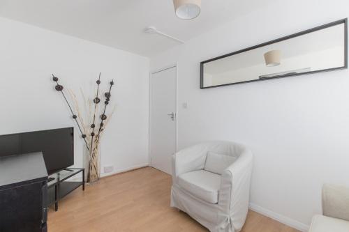 a living room with a white chair and a mirror at Stylish Stays by Russel Square in London