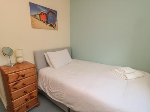 a bedroom with a bed and a dresser with a mirror at Sandy Cove in Chathill