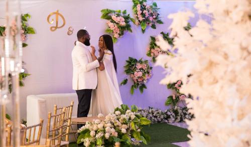 a bride and groom standing in front of a wall with flowers at Chateux De Atlantique Hotel in Lagos