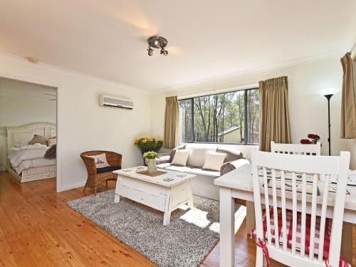 ein Wohnzimmer mit einem Sofa und einem Kinderbett in einem Zimmer in der Unterkunft Olive Grove 3 1 Bedroom Villa with large Bath in Pokolbin