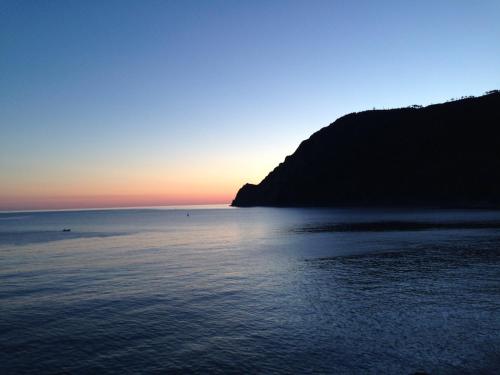 una puesta de sol sobre un cuerpo de agua con una montaña en Il Portico, en Monterosso al Mare