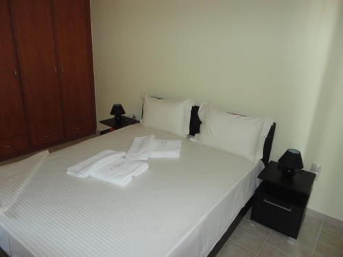 - un lit avec des draps blancs et des serviettes dans l'établissement Luxury House Diakopto, à Diakopto