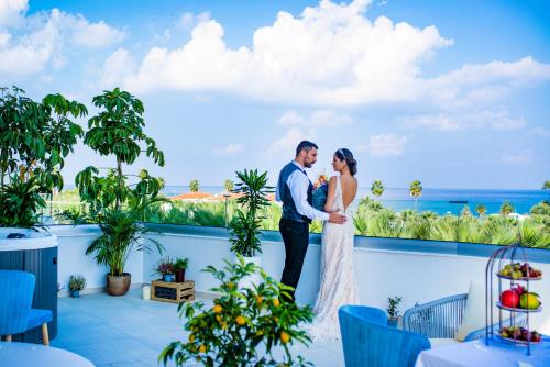 a bride and groom standing on the balcony of their wedding at At Herbal Boutique Hotel & Spa in Protaras
