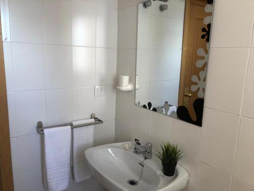 Un baño blanco con lavabo y espejo. en IMEDA Estudios LOS VALLES CON PARKING, en Sierra Nevada