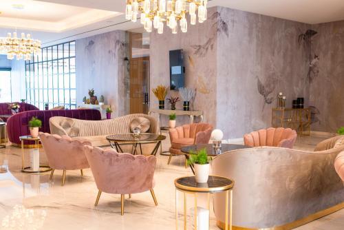 a lobby with pink chairs and tables and a chandelier at At Herbal Boutique Hotel & Spa in Protaras