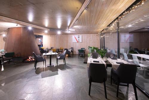 a restaurant with tables and chairs and a fireplace at Pensiunea Atra Doftana in Teşila