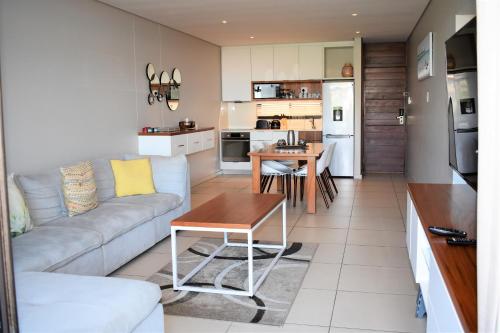 a living room and kitchen with a couch and a table at Zimbali Suites 407, Capital Hotel Complex in Ballito
