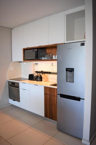 Una cocina con gabinetes blancos y un refrigerador. en Zimbali Suites 407, Capital Hotel Complex, en Ballito