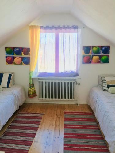 a room with two beds and a window and a rug at Arthome Småland in Ruda