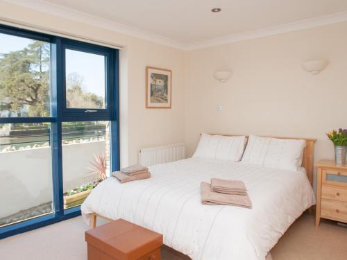 una camera da letto con un grande letto bianco e una finestra di 1 Crabshell Quay a Kingsbridge