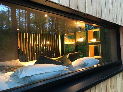 a window display of a bed with white pillows at Forest Cube in Oignies-en-Thierache