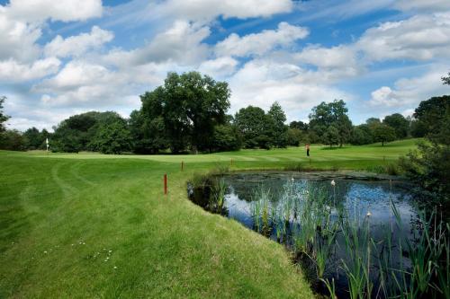 a golf course with a pond on a green at The Tytherington in Macclesfield