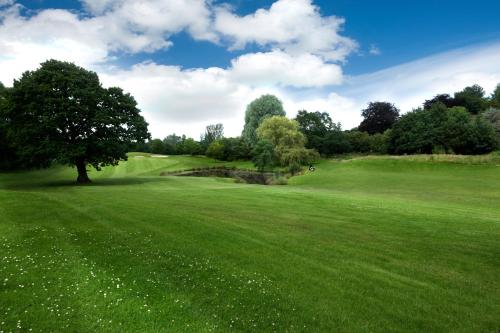 a green field with a tree in the middle of it at The Tytherington in Macclesfield