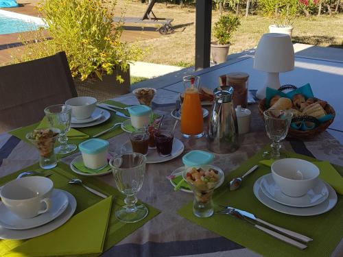 ein Tisch mit Tellern voller Speisen und Getränken in der Unterkunft La Vigneraie de Laura in Sainte-Colombe