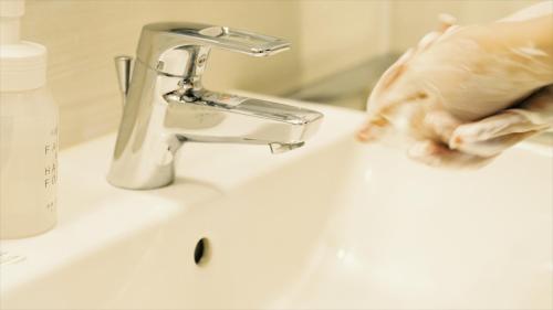 a person washing their hands next to a sink at Tokyu Stay Hakata in Fukuoka