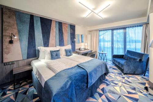 a bedroom with a large bed and a blue chair at Wellton Riverside SPA Hotel in Riga