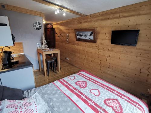 um quarto com uma parede de madeira, uma cama e uma televisão em La Cabane em Chamonix-Mont-Blanc