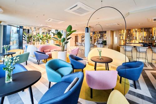 un restaurante con mesas y sillas azules y un bar en Wellton Riverside SPA Hotel en Riga