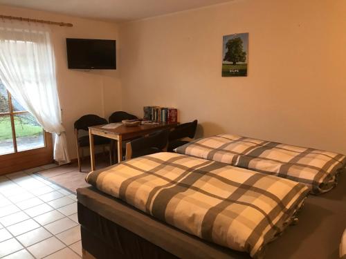 two beds in a room with a table and a television at Appartement Hildegard in Rieden am Forggensee
