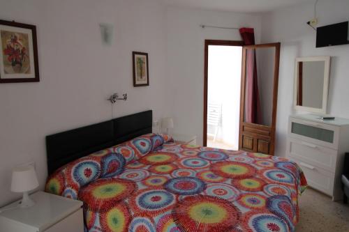 a bedroom with a bed with a colorful bedspread at Hostal Fornet Altea in Altea