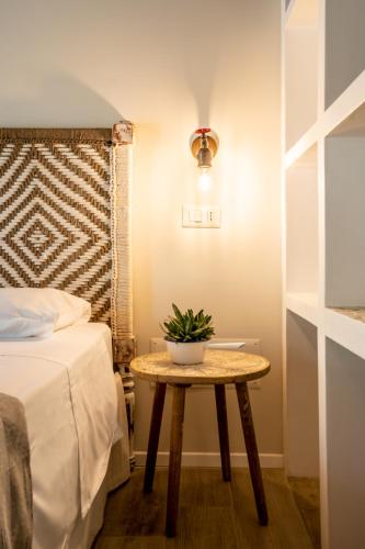 a small table with a plant on it next to a bed at Casa Stones B&B in Cugnana