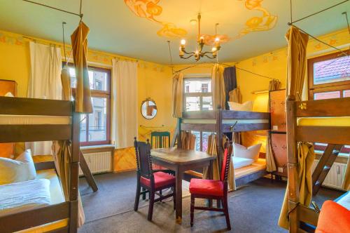 Zimmer mit einem Tisch, Stühlen und Etagenbetten in der Unterkunft Hostel Lollis Homestay Dresden in Dresden