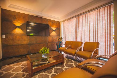 a living room with two chairs and a tv at Hotel Rafain Centro in Foz do Iguaçu